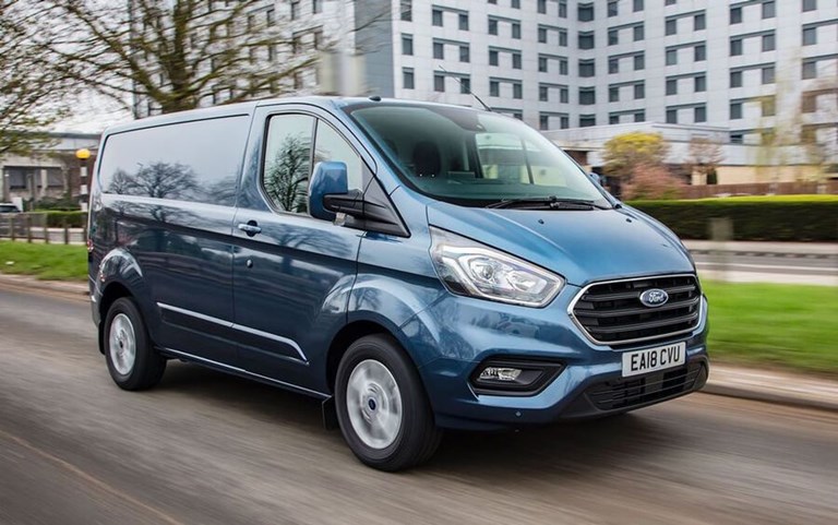 Modern, blue Ford Transit hire van parked on the street in front of high-rise flats.