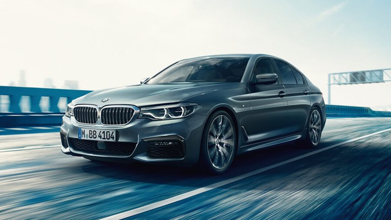 High-performance, executive rental car driving across a bridge in the city.