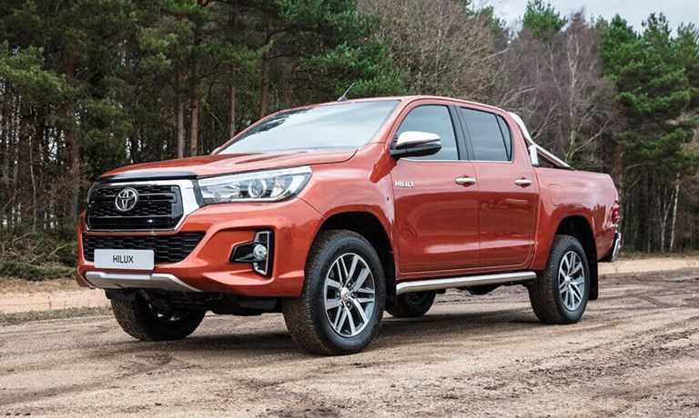 Toyota Hilux pick-up truck parked on a dirt road next to a forest.